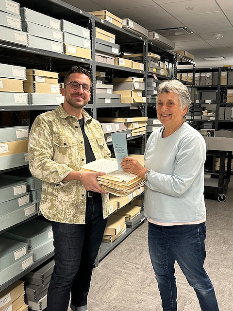 two people in room with open shelves handling documents